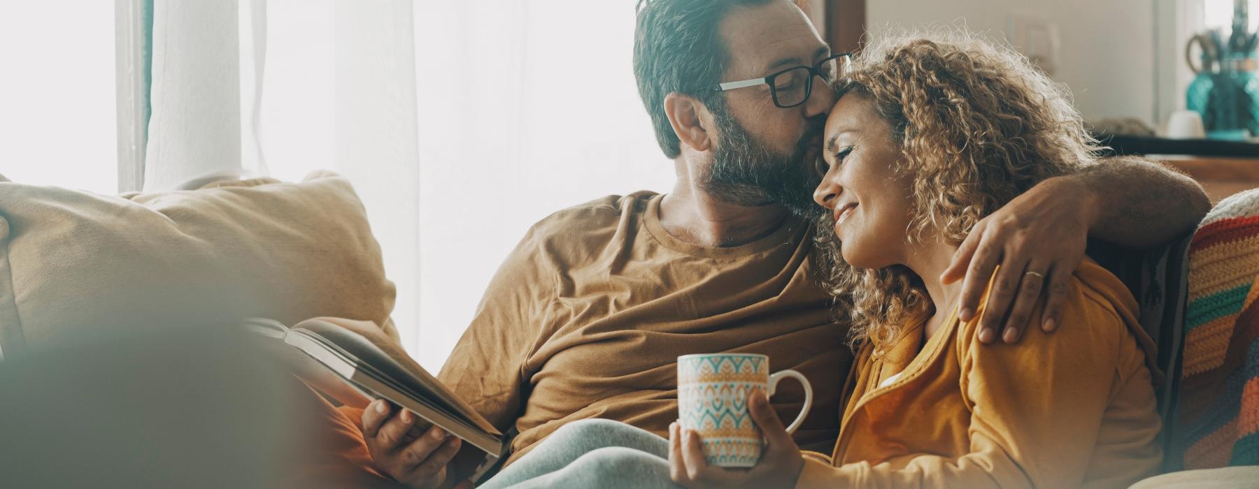 a man and woman sitting on a couch and looking at a cell phone