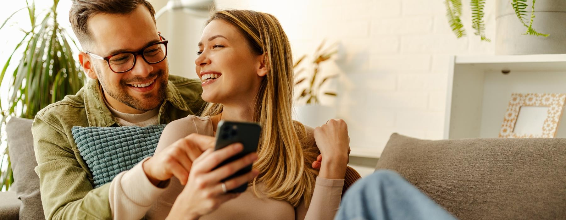 a man and a woman sitting on a couch looking at a cell phone